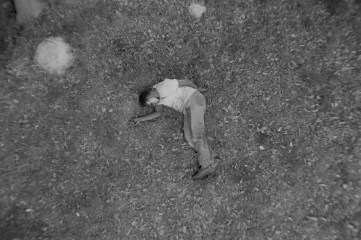 Joe, a Black man, wearing a T-shirt and trousers, is lying on the ground. From Ibrahim Shaddad’s ‘Hunting Party.’ Courtesy of Flaherty Seminar.
