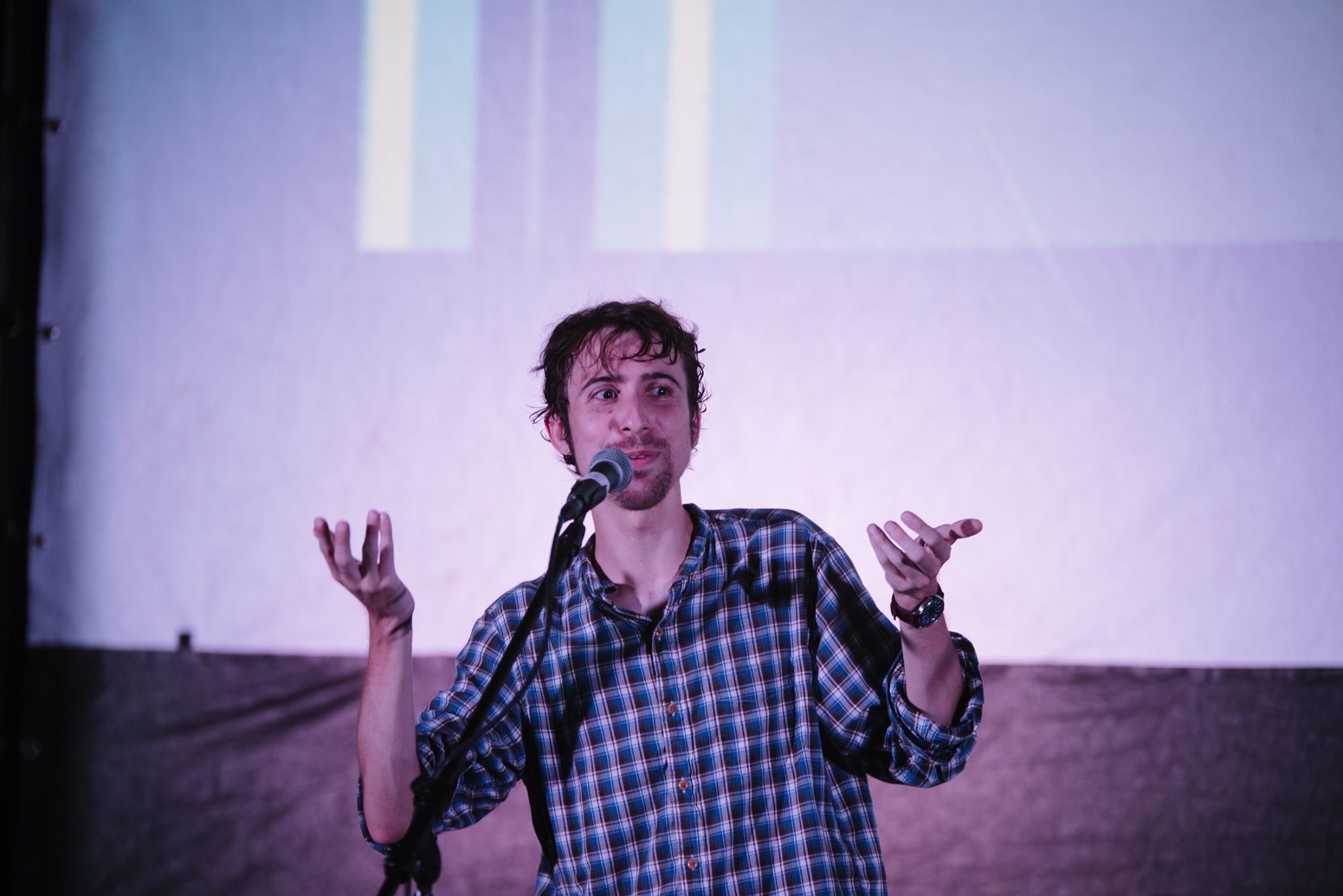 Chris Boeckmann, one of the Getting Real ‘22’s programmers, talks into a microphone with his arms raised. Photo courtesy of Rebecca Allen. 